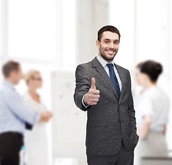 Image showing handsome buisnessman showing thumbs up in office