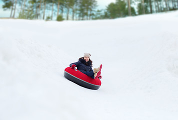 Image showing happy teenage girl sliding down on snow tube