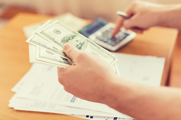 Image showing close up of man counting money and making notes