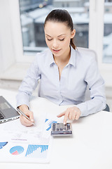 Image showing businesswoman with laptop and charts in office