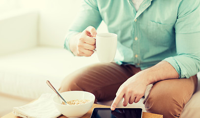 Image showing close up of man with tablet pc having breakfast