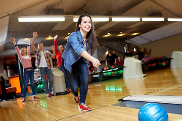 Image showing happy young woman throwing ball in bowling club