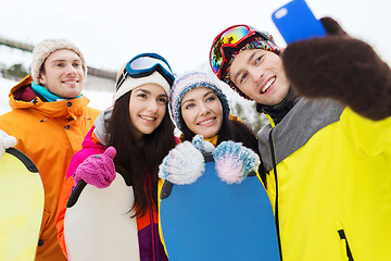 Image showing happy friends with snowboards and smartphone