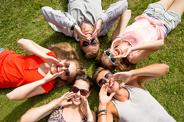 Image showing group of smiling friends lying on grass outdoors