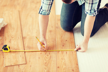 Image showing close up of male hands measuring wood flooring