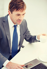 Image showing smiling businessman working with laptop computer