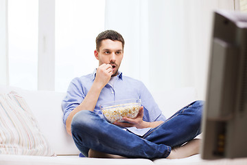 Image showing man watching tv and eating popcorn at home