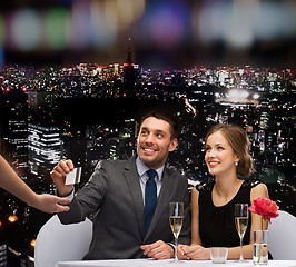 Image showing smiling couple paying for dinner with credit card