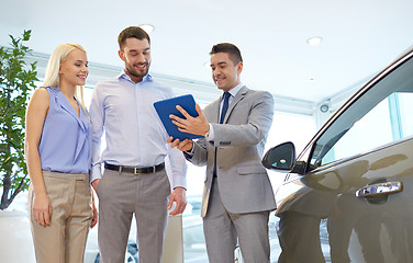 Image showing happy couple with car dealer in auto show or salon