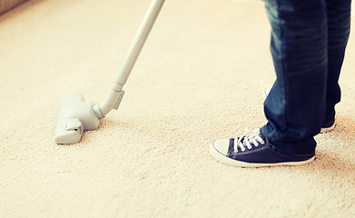 Image showing close up of male hoovering carpet