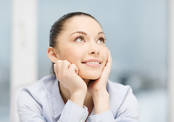 Image showing smiling businesswoman dreaming in office