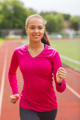 Image showing smiling woman running on track outdoors