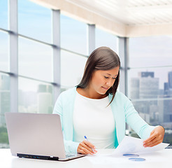 Image showing smiling woman with laptop computer and papers