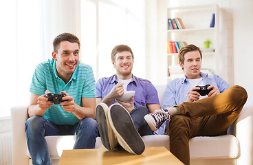 Image showing smiling friends playing video games at home