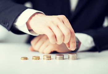 Image showing man putting stack of coins into one row