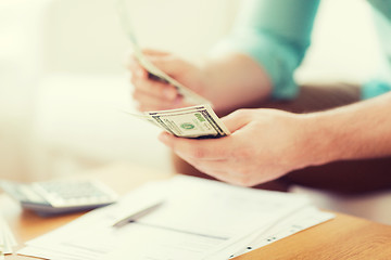 Image showing close up of man counting money and making notes