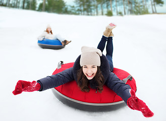 Image showing group of happy friends sliding down on snow tubes