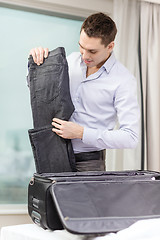 Image showing businessman packing things in suitcase