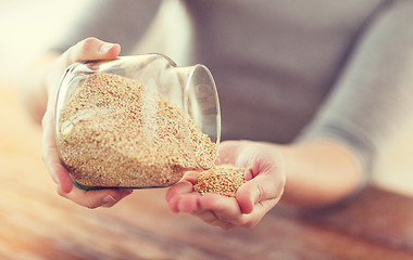 Image showing close up of female emptying jar with quinoa