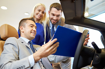 Image showing happy couple with car dealer in auto show or salon