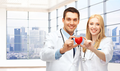 Image showing happy young doctors cardiologists with red heart