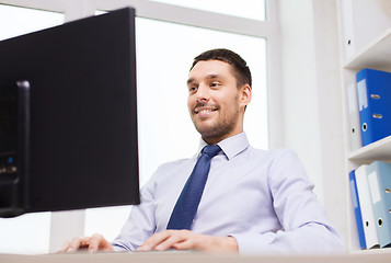 Image showing smiling businessman with computer in office