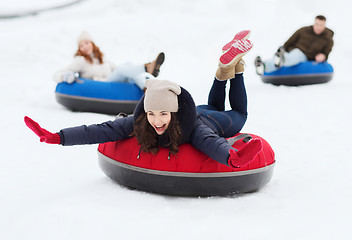 Image showing group of happy friends sliding down on snow tubes