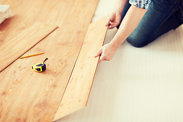 Image showing close up of male hands intalling wood flooring