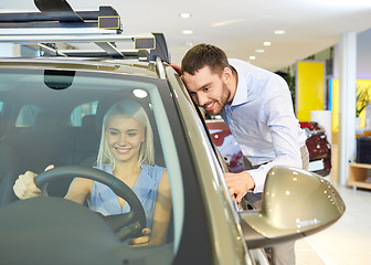 Image showing happy couple buying car in auto show or salon