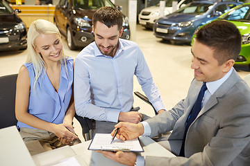 Image showing happy couple with car dealer in auto show or salon