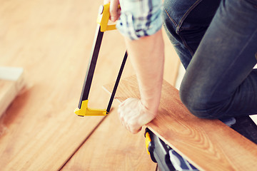 Image showing close up of male hands cutting parquet floor board