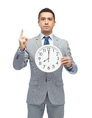 Image showing businessman in suit holding clock with 8 o'clock