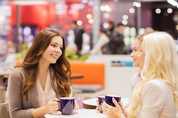 Image showing smiling young women drinking coffee in mall 