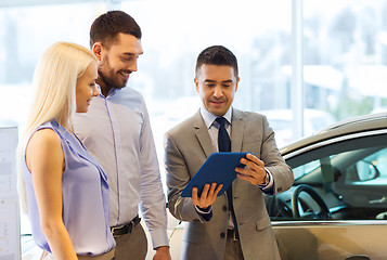 Image showing happy couple with car dealer in auto show or salon