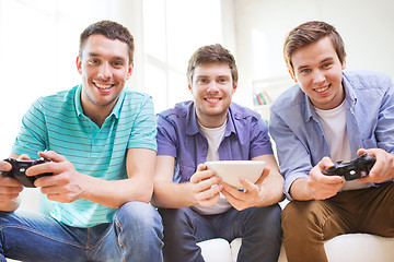 Image showing smiling friends playing video games at home