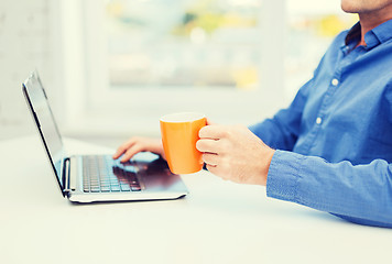 Image showing male hand with cup of tea or coffee and laptop