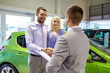 Image showing happy couple with car dealer in auto show or salon