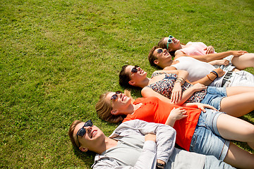 Image showing group of smiling friends lying on grass outdoors