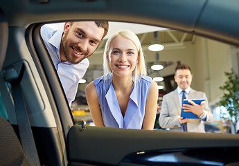 Image showing happy couple with car dealer in auto show or salon