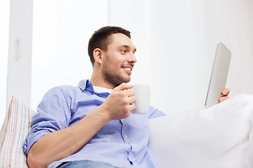 Image showing smiling man with tablet pc and cup at home