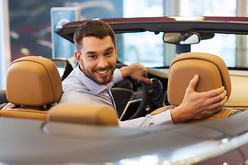 Image showing happy man sitting in car at auto show or salon