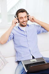 Image showing smiling man with laptop and headphones at home