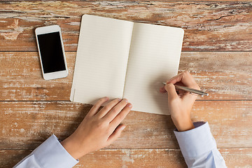 Image showing close up of hands with notebook and smartphone