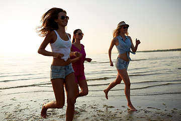 Image showing group of smiling women running on beach