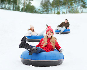 Image showing group of happy friends sliding down on snow tubes