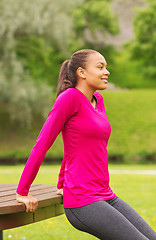 Image showing smiling woman doing push-ups on bench outdoors