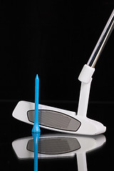 Image showing Golf putter and gold equipments on the black glass desk