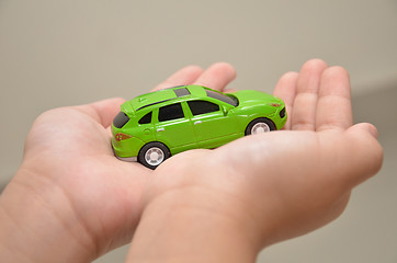 Image showing Green toy car on a right hand