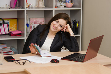 Image showing employee with a smile, looking into frame before opening notepad