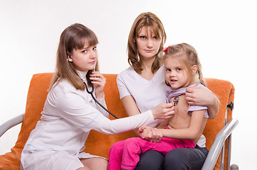 Image showing Pediatrician listening stethoscope breast girl sitting on mothers hands